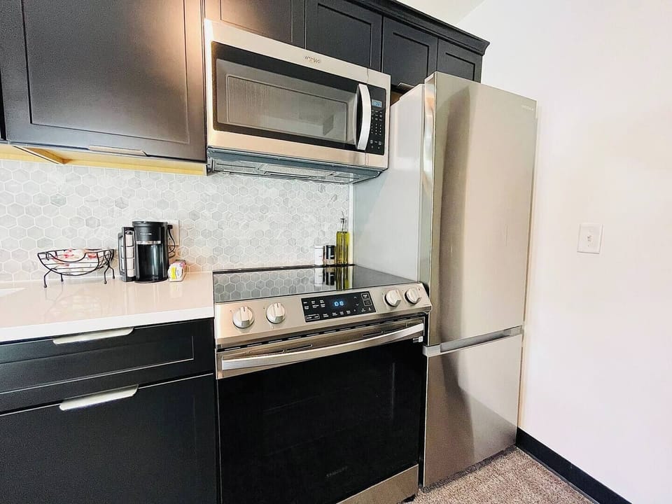 Stylish kitchen with dark cabinetry, stainless steel appliances, and a well-appointed coffee station for your morning needs.