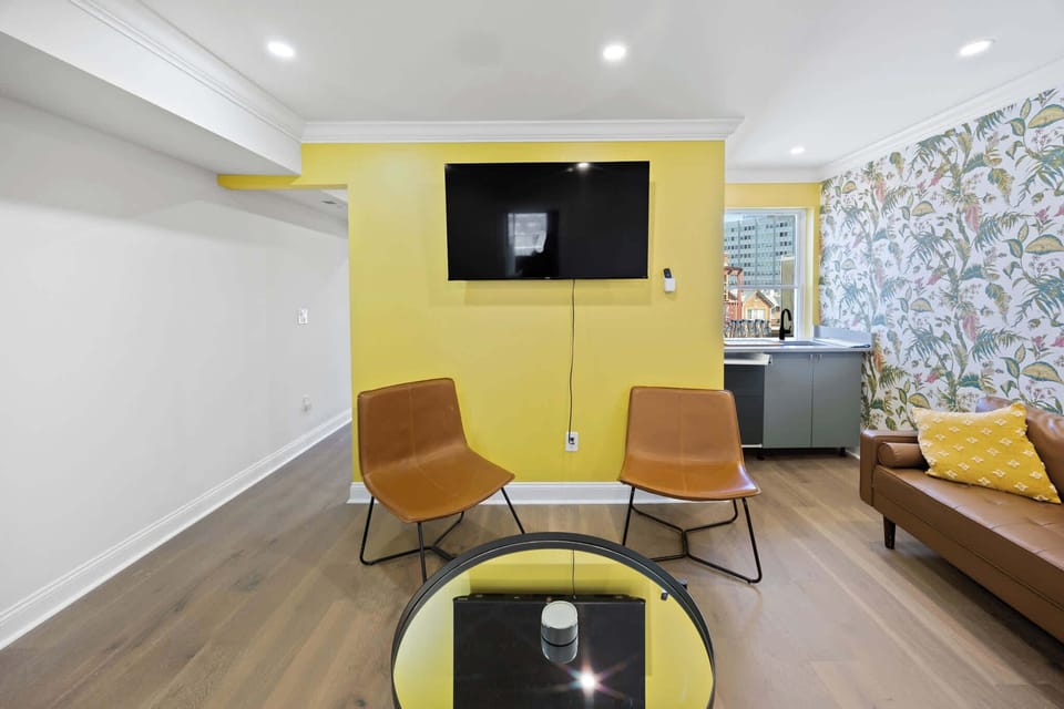 Relax in this bright and modern living room featuring bold patterns, cozy seating, and a large TV for entertainment.