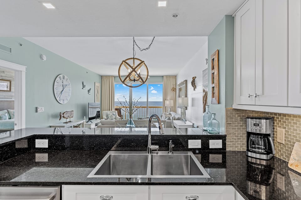 Prepare meals with stunning ocean views from this modern kitchen, featuring sleek granite counters and bright coastal charm—perfect for your beach getaway.