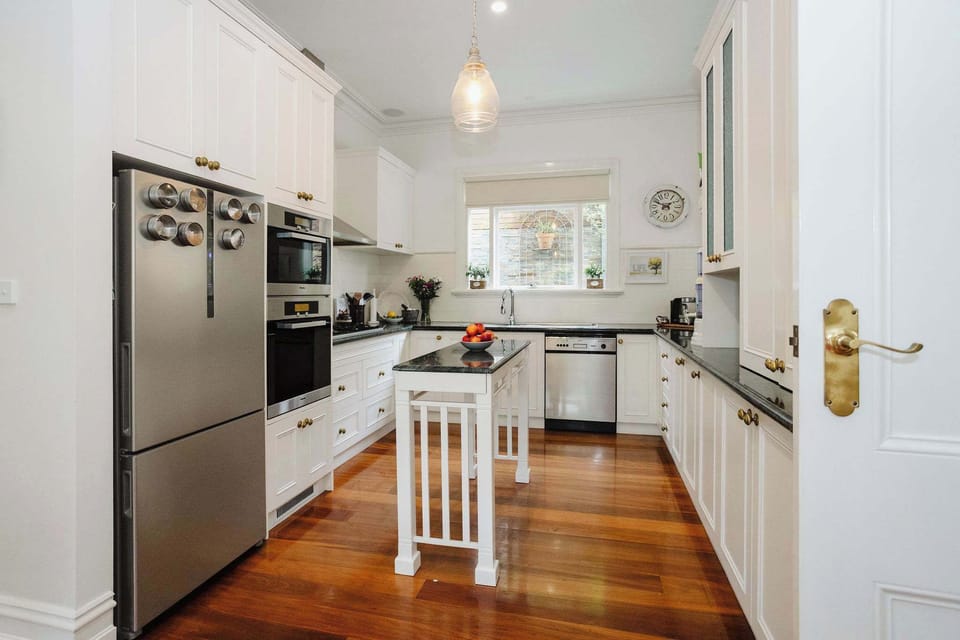 Well-equipped kitchen featuring an overhead dishwasher, a sleek cooktop, a spacious fridge, and ample counter space, designed for ease and functionality in meal preparation.