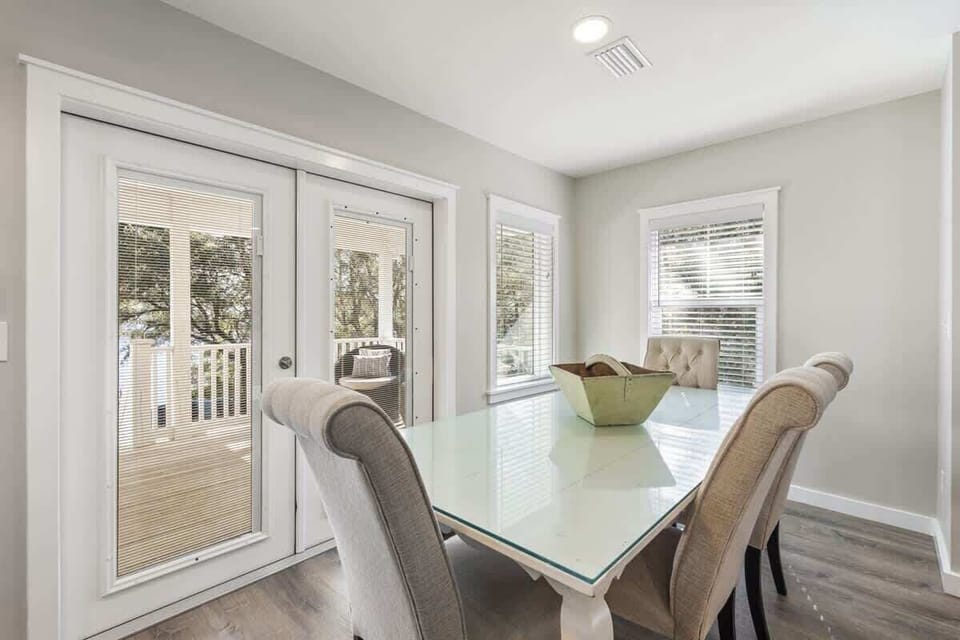 - Dining area with large windows & access to the porch, offering a beautiful view - Elegant chairs around a glass table create a cozy setting for meals or casual conversations - Neutral tones add to the peaceful & welcoming atmosphere of the space