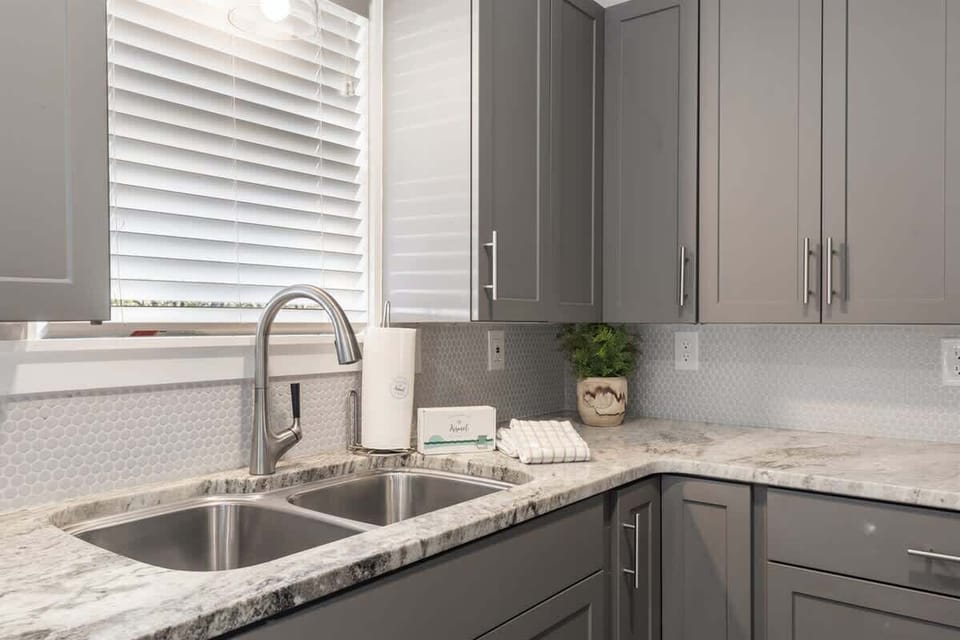 - Stylish kitchen corner with a double sink and beautiful granite countertops - Modern cabinetry with plenty of storage space and a touch of greenery for a fresh feel - Plenty of natural light streaming through the window to brighten the space