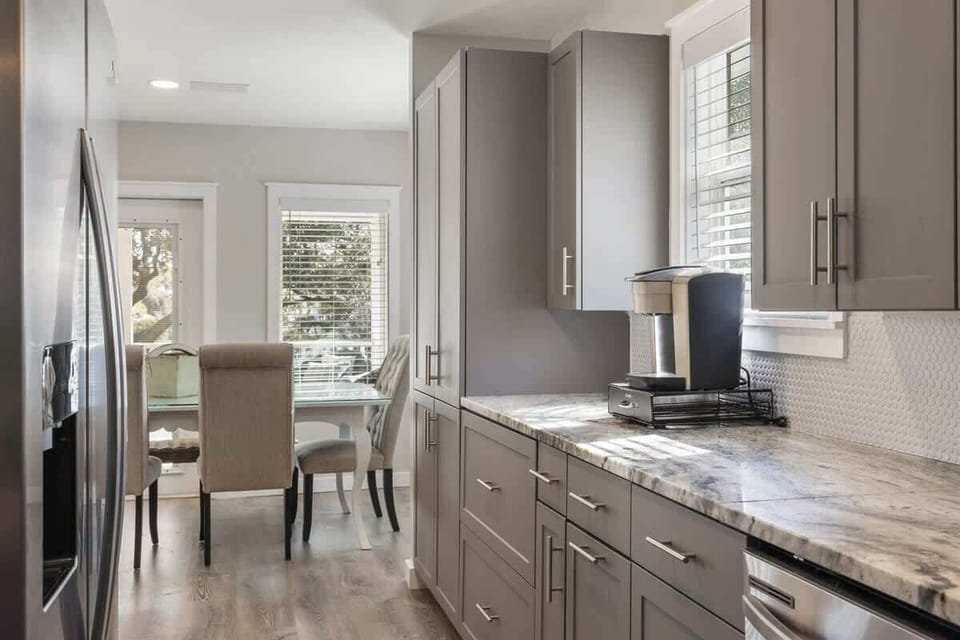 - Sleek kitchen with modern cabinetry & a stylish coffee corner - Spacious countertop perfect for meal prep, easy access to natural light & the dining area - Windows provide a bright atmosphere, while the coffee maker adds a cozy touch for morning ro