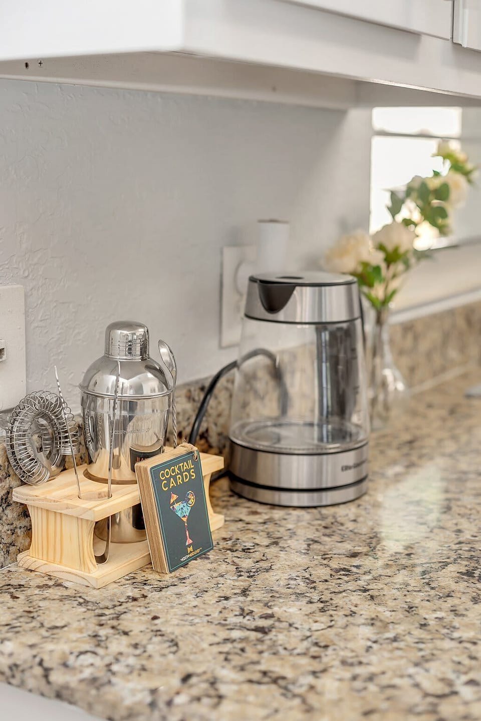 Granite kitchen countertop with a cocktail shaker set and electric kettle for convenient beverage preparation.