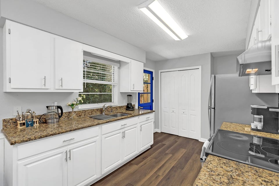 Modern kitchen with granite countertops and a vibrant blue door for natural light.
