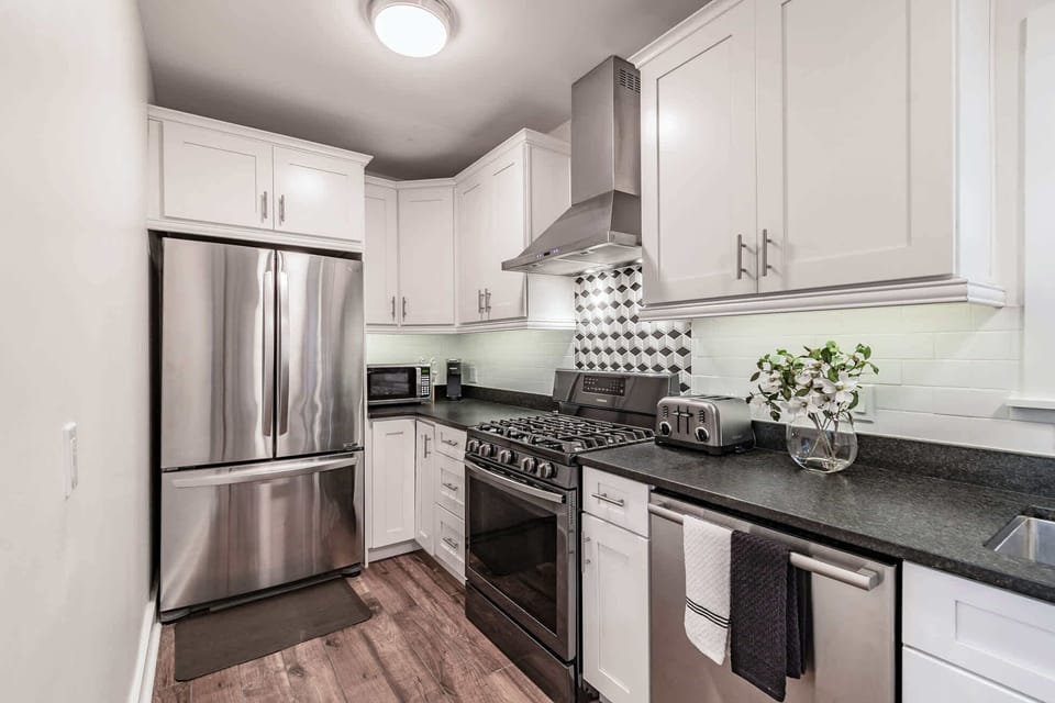 St Pete vacation rental kitchen with white cabinets, stainless appliances and designer backsplash 