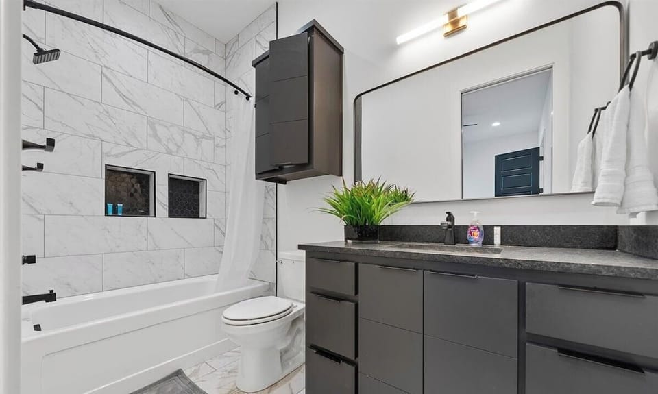 A bright and airy bathroom featuring elegant tilework, a shower-tub combination, and modern finishes for a fresh, contemporary feel.