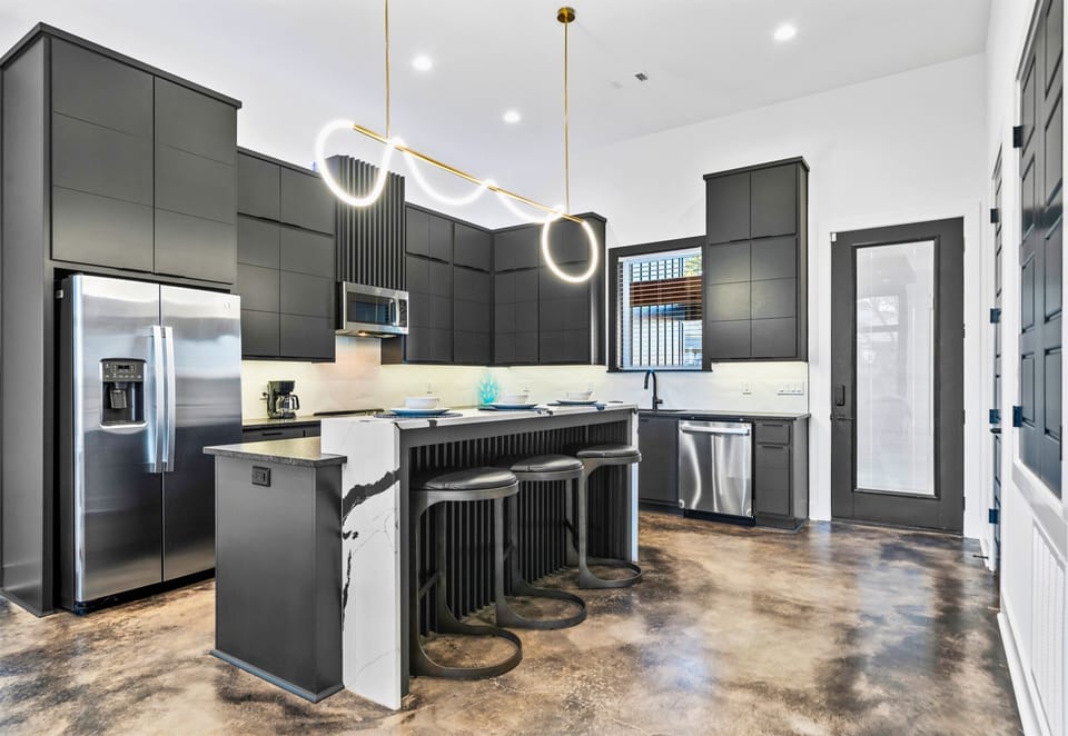 The kitchen’s open-concept design features bold lighting, high-end appliances, and a layout that’s perfect for entertaining or family gatherings.