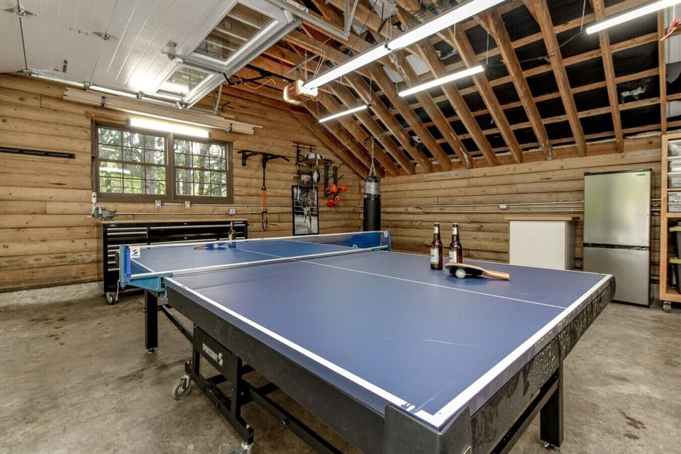 Detached heated game room with ping pong, boxing gear, and beverage fridge.