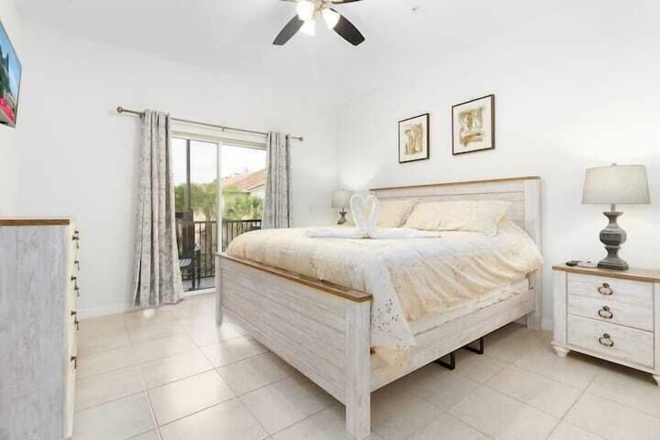 This bright and inviting master bedroom features a plush king-sized bed, stylish furnishings, and direct access to a private balcony, perfect for enjoying peaceful views.