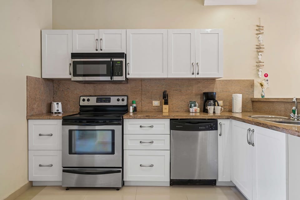 A bright and inviting kitchen with modern appliances, ample storage cabinets, and a front-facing pool view that fills the space with natural light is perfect for a booking retreat!
