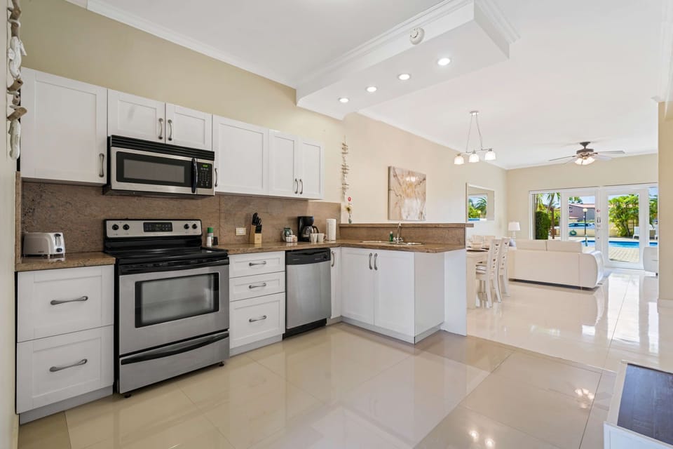 A bright and inviting kitchen with modern appliances, ample storage cabinets, and a front-facing pool view that fills the space with natural light is perfect for a booking retreat!