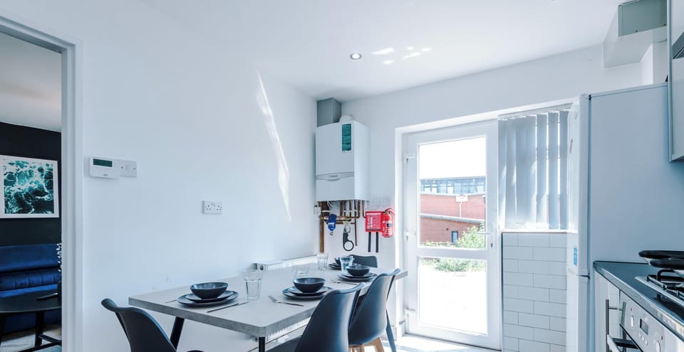 This modern dining area is perfectly situated within the kitchen, creating a bright and social heart for the home. It features a sleek, grey dining table paired with four stylish black chairs with wooden legs, offering a clean and contemporary look.