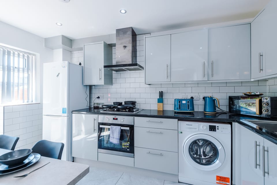 Integrated appliances, including a washing machine and oven, are neatly built into the sleek cabinetry for a streamlined look.
