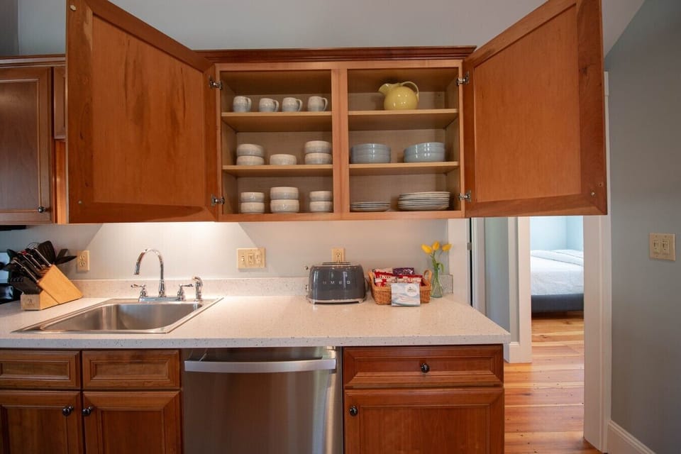 Fully stocked kitchen with everyday essentials, including plates, bowls, glasses, mugs, wine glasses, silverware, pots and pans, cooking utensils, knives and cutting boards, measuring cups and spoons, mixing bowls, and more.