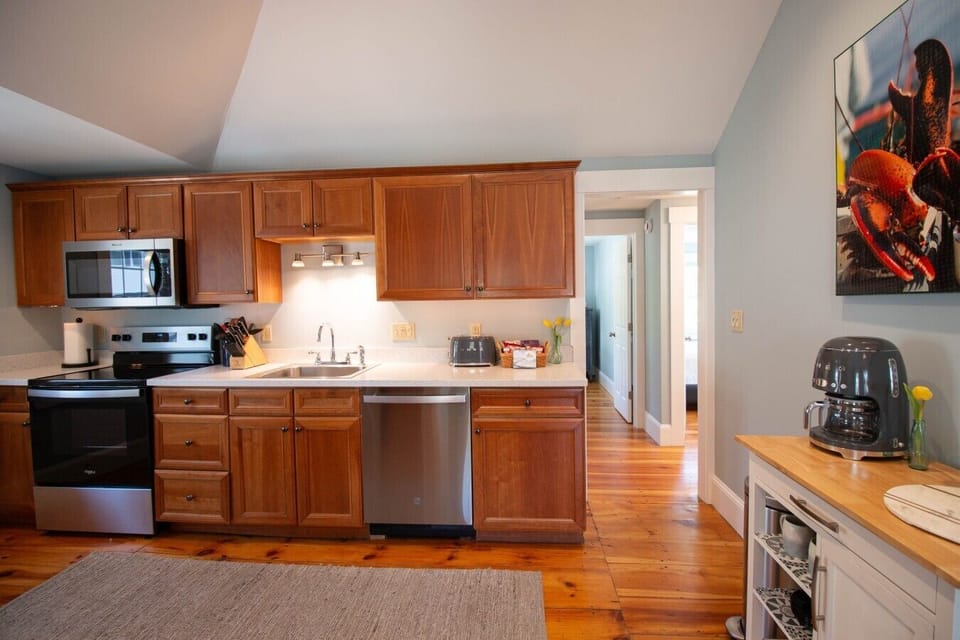 The kitchen is equipped with an electric stove, microwave, large sink with a garbage disposal, dishwasher, full-size refrigerator, and a stylish Smeg toaster.