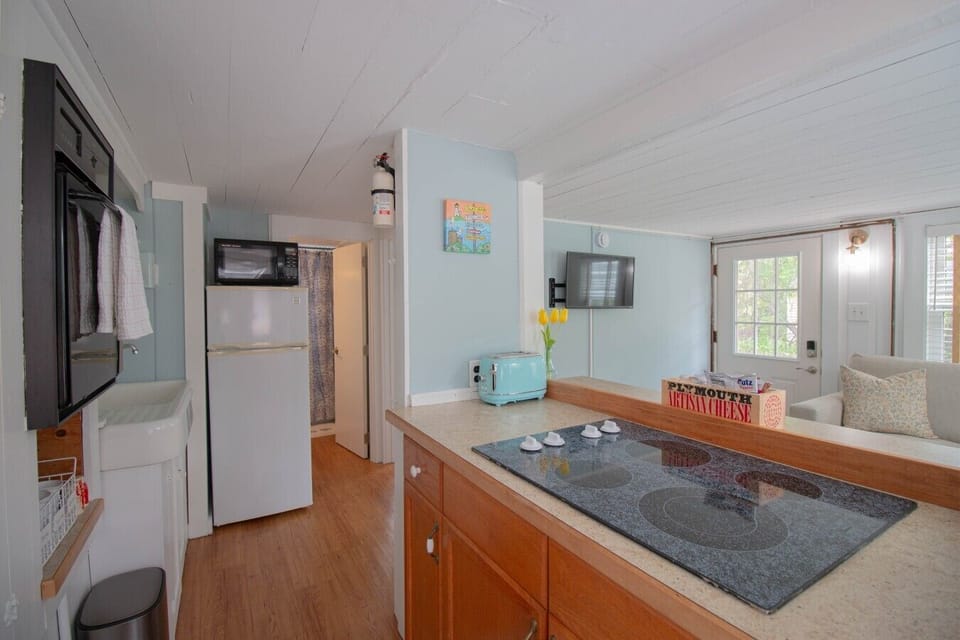 The kitchen includes an electric stovetop and oven, a medium-sized refrigerator, microwave, toaster, and a standard coffee maker for your convenience.