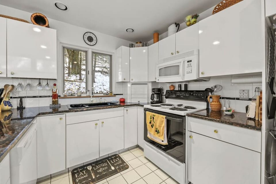 Fully equipped kitchen with white cabinetry, gas stove, and dishwasher.