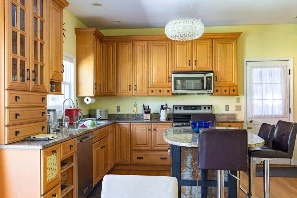 Well-equipped kitchen featuring stainless steel appliances, granite countertops, and natural wood cabinetry.