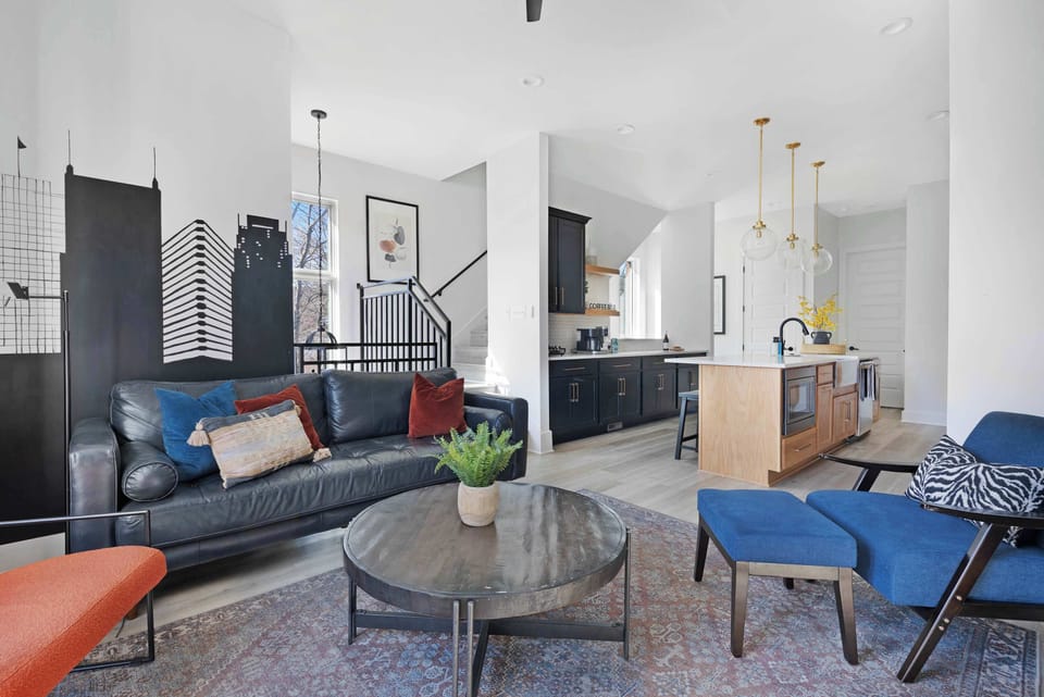 Stylish living room featuring a wall-mounted smart TV, cozy leather couch, sleek coffee table, and three elegant accent chairs for a comfortable and inviting space