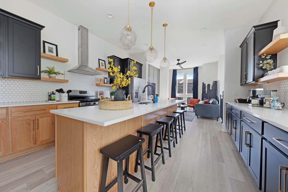 Fully equipped kitchen with a spacious pantry and a large island with five barstools, perfect for meal prep and casual dining.