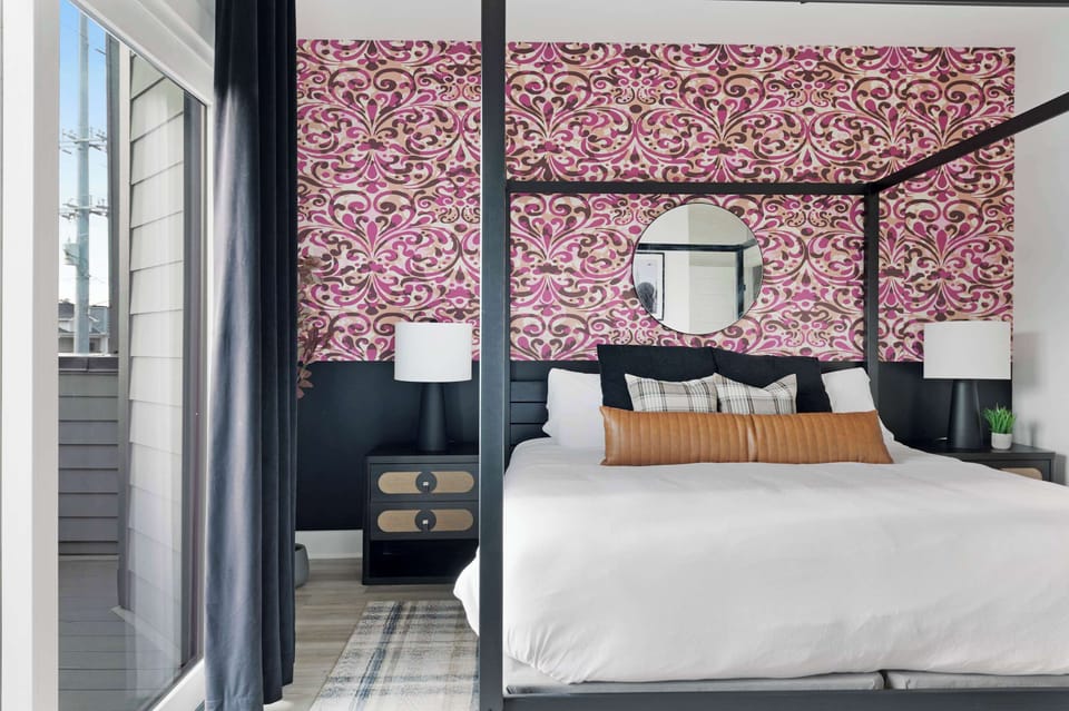Cozy bedroom with a king bed, walk-in closet, and private balcony with two chairs. The en-suite bathroom features a modern shower for added comfort.