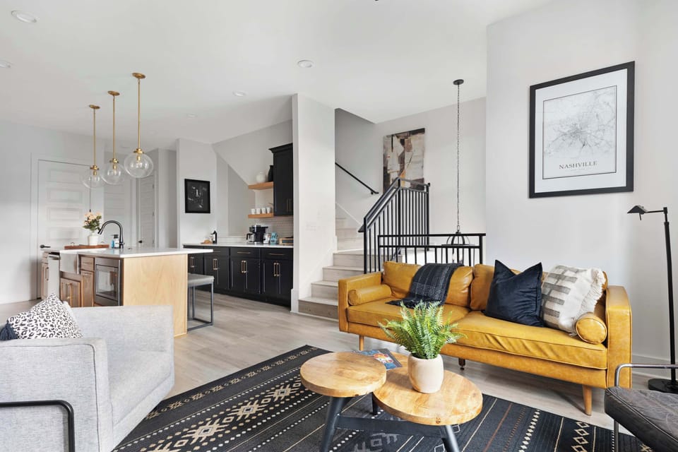 Inviting living room with a wall-mounted smart TV, comfortable leather couch, sleek coffee table, and three stylish accent chairs, creating a cozy and functional space.
