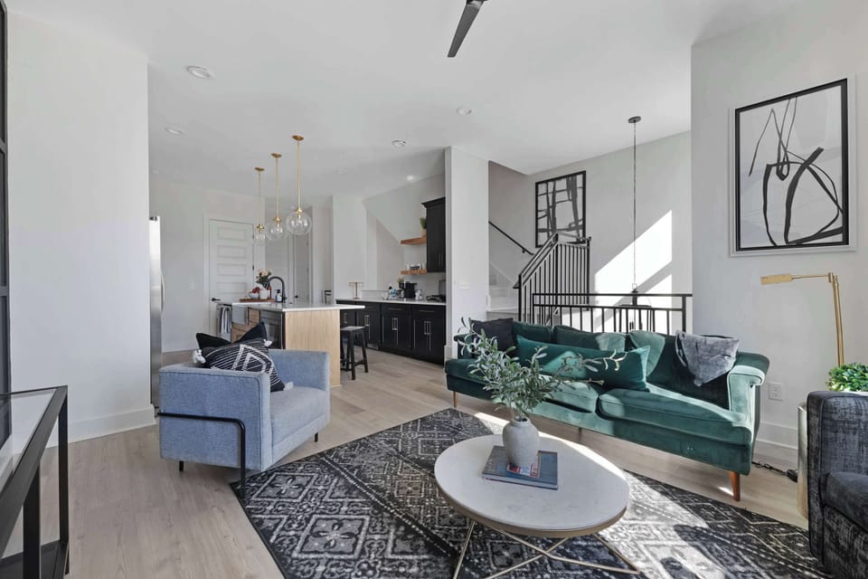 Chic living room featuring a wall-mounted smart TV, a plush velvet couch, a stylish coffee table, and three accent chairs, offering a cozy yet elegant atmosphere