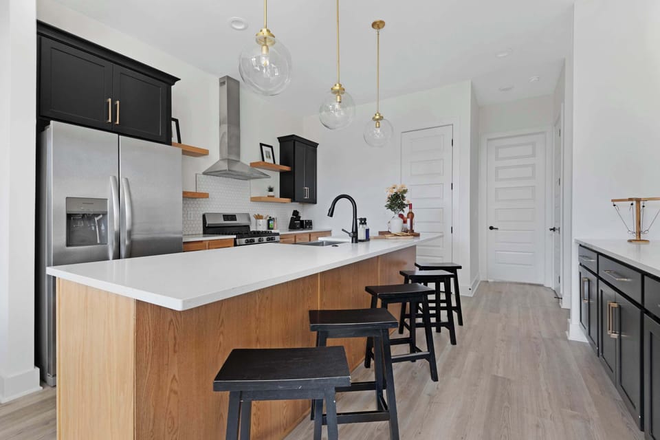 Modern kitchen with a spacious pantry and a large island with five barstools, ideal for cooking and casual dining