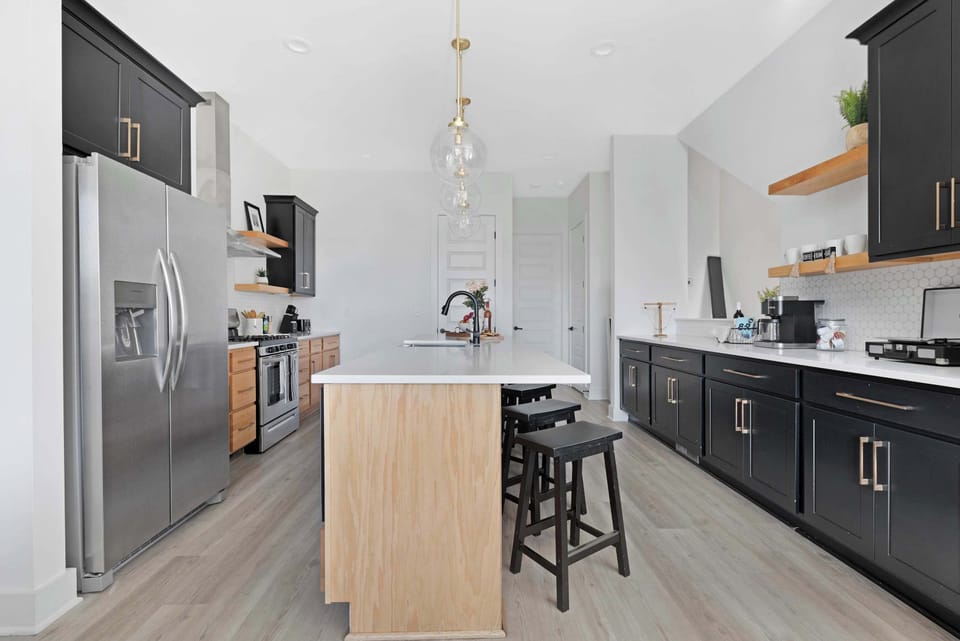 Modern kitchen with a spacious pantry and a large island with five barstools, ideal for cooking and casual dining