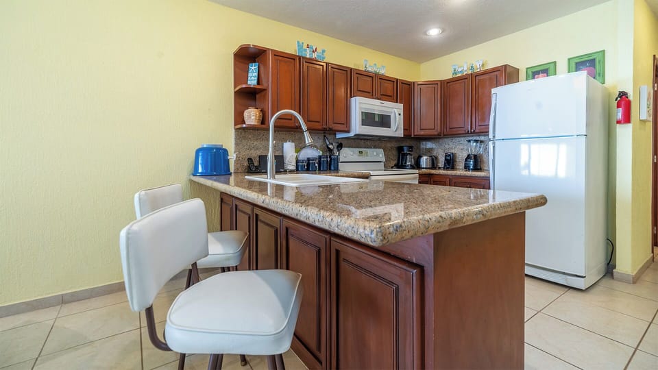 Two chairs adorn the granite counter, making just the place to hang out ask make a meal.