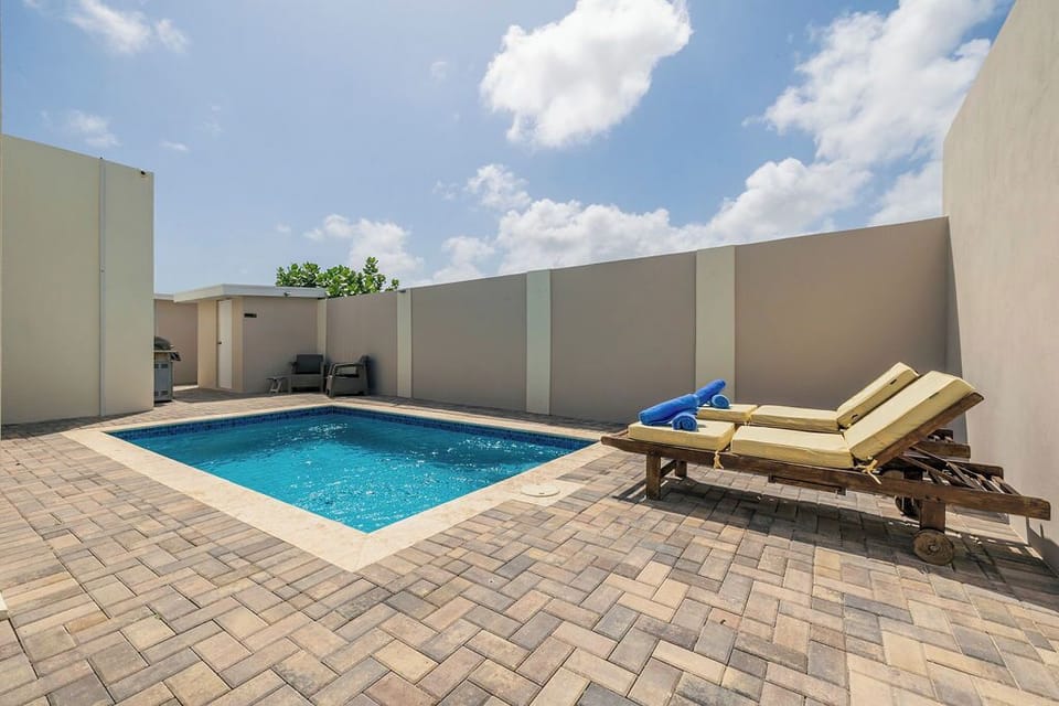 Private pool area with sun loungers and blue sky overhead, offering a tranquil outdoor retreat within the enclosed courtyard of the property.