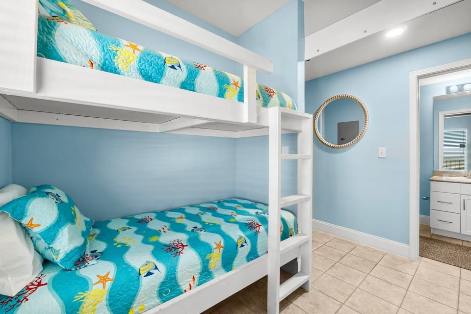 Cozy bunk bed room with ocean-themed bedding and soft blue walls.