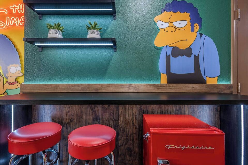 Experience a lively eatery with vibrant green walls, nostalgic touches, striking artwork, and retro red stools. The illuminated shelves create a modern vibe, making it the ideal spot for gatherings or late-night snacks.