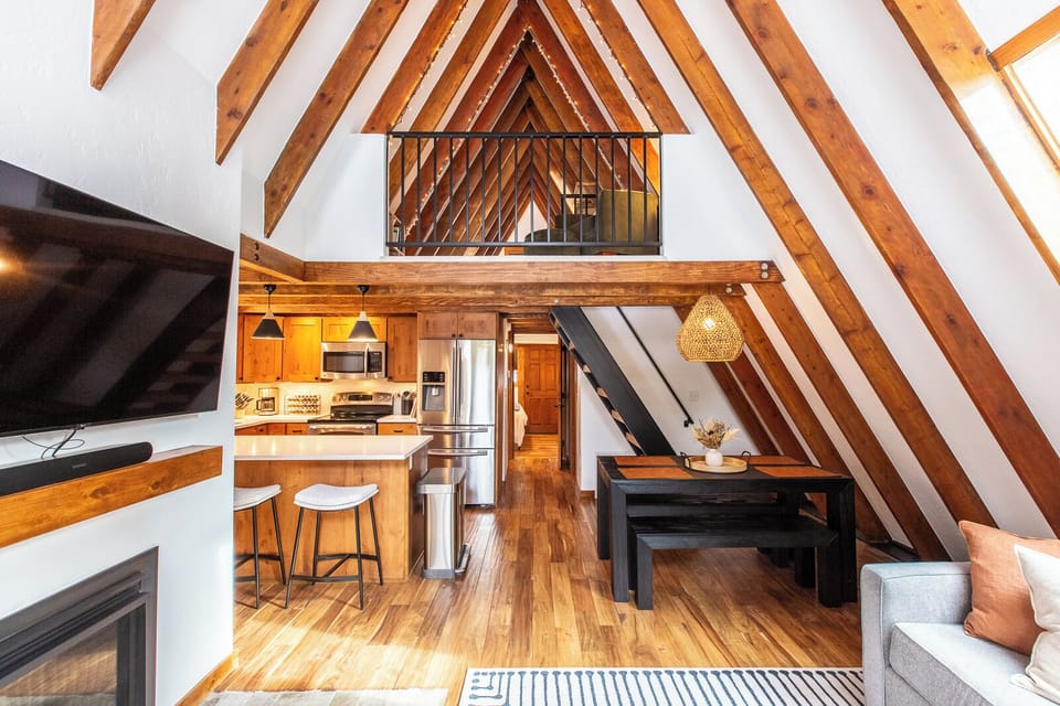 A frame style cabin with lofted bedroom and cozy living room with fireplace. 