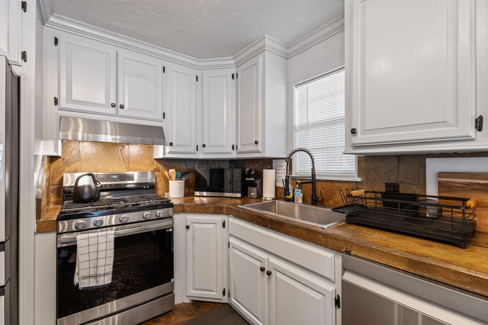 Full kitchen featuring butcher block counters, gas range, and classic cabinetry with modern hardware.
