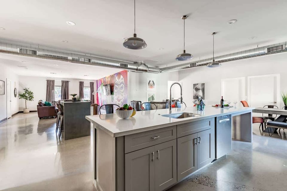 Unit 1: Fully equipped modern kitchen featuring stainless steel appliances, kitchen island with bar seating for 4 guests and a formal dining table with seating for 8 guests.