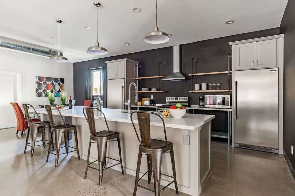 Unit 1: Fully equipped modern kitchen featuring stainless steel appliances, kitchen island with bar seating for 4 guests and a formal dining table with seating for 8 guests.