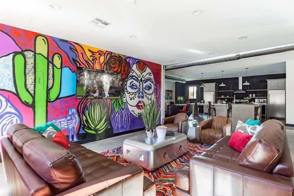 Unit 1: Open-floor living space featuring a Smart TV, designer furnishings, a beautiful mural on the wall, dining table, and a pool table.