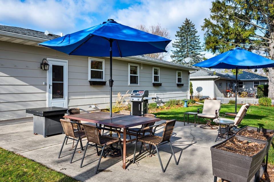 Large backyard with seating, gas grills and a fire table. 