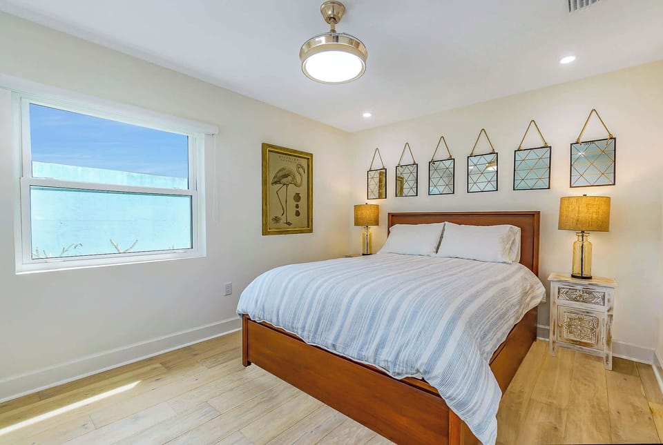 Bright bedroom with a wooden bed frame and decorative mirrors above the headboard