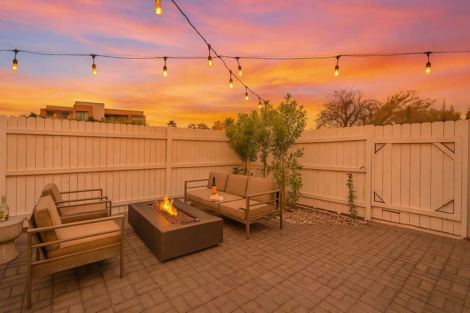 Outdoor dining table, lounge area with fire pit, & sun loungers.