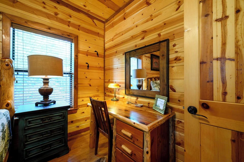 Your private retreat features warm wood walls and a cozy desk space where you can unwind with soft lamplight and peaceful views through the window.