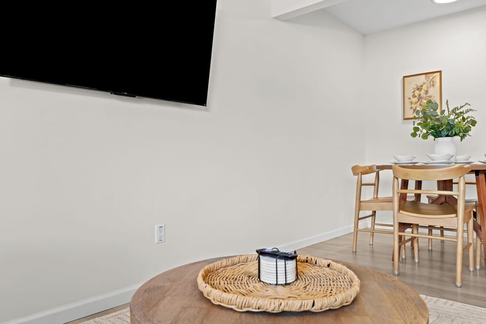 Enjoy a bright and airy space with elegant wall paneling, a mounted Smart TV, and modern furnishings.