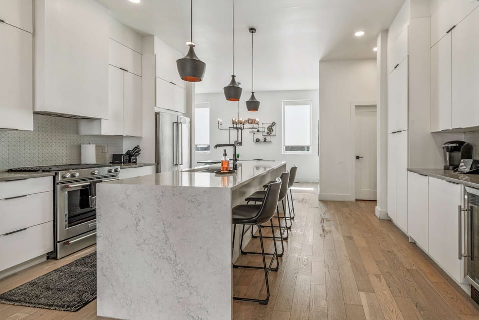 Elegant white marbled island featuring three bar stools.