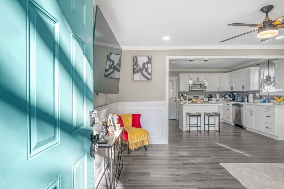 Relax in a cozy and modern space with a comfy sofa, large flat-screen TV, and ceiling fan. Natural light and an open layout flow seamlessly into the kitchen, creating a warm and inviting vibe.