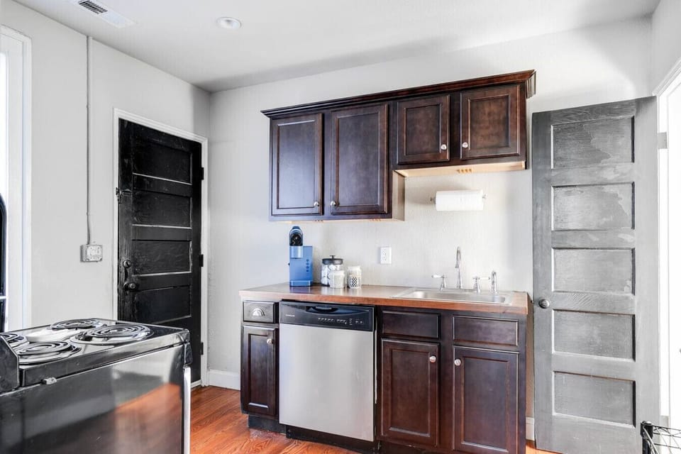 A fully equipped, well-lit space with an oven range, Keurig, dishwasher, and thoughtful touches like a paper towel dispenser. Perfect for whipping up meals or enjoying your morning coffee.
