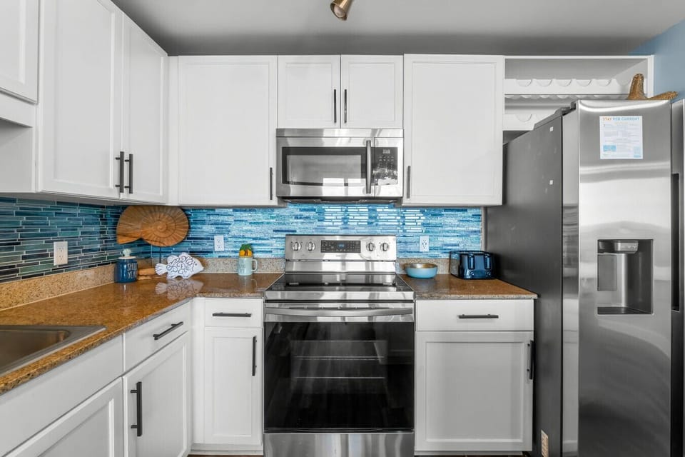 modern kitchen with stainless steel appliances, stylish blue backsplash, and all the essentials for your culinary needs