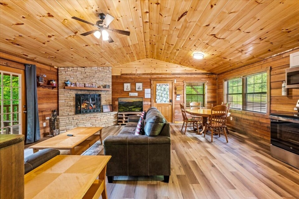 Kick back in this cozy living room with plush seating, warm wood walls, and a stone fireplace that anchors the space. It’s made for movie nights, morning coffee, and slow mountain evenings.