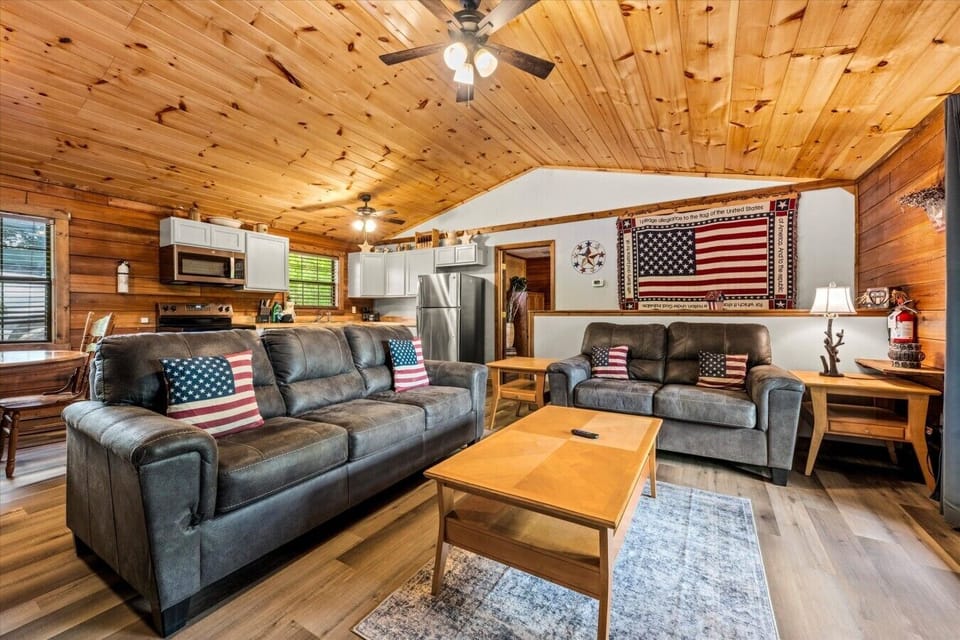 Settle into this cozy mountain living room with plush seating, warm wood walls, and a stone fireplace that invites slow mornings and relaxed evenings. The perfect spot to unwind after a day exploring the Smokies.